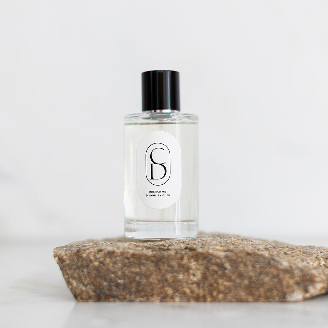 Clear bottle with black cap on a stone surface against a light background