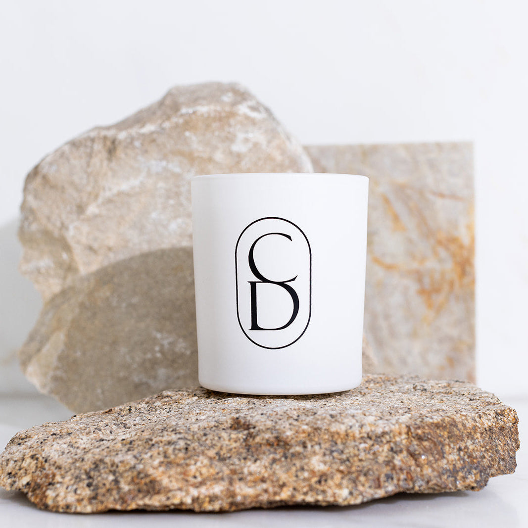 White candle with a logo on a rock with a white background