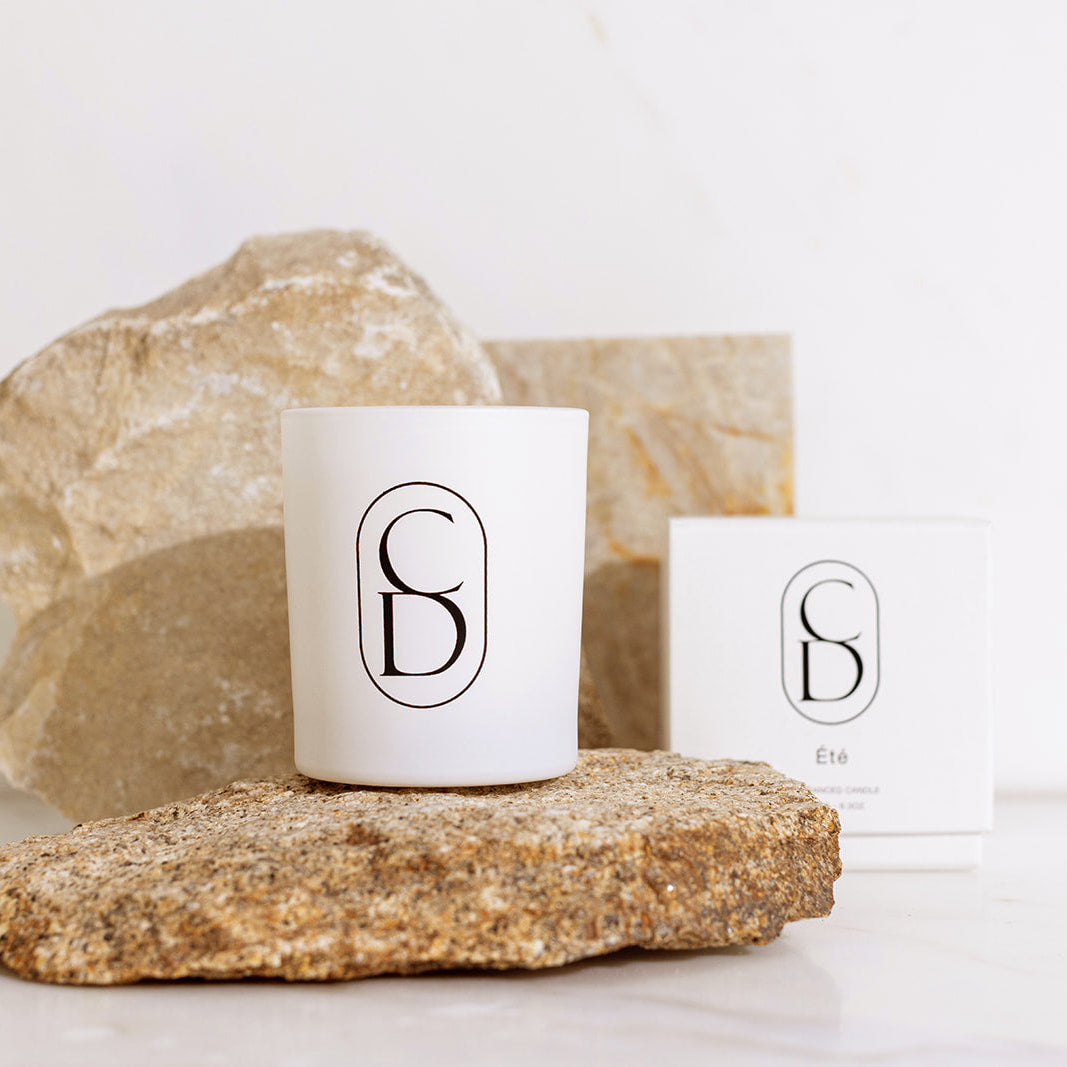 White candle with a logo on a rock, with a white background
