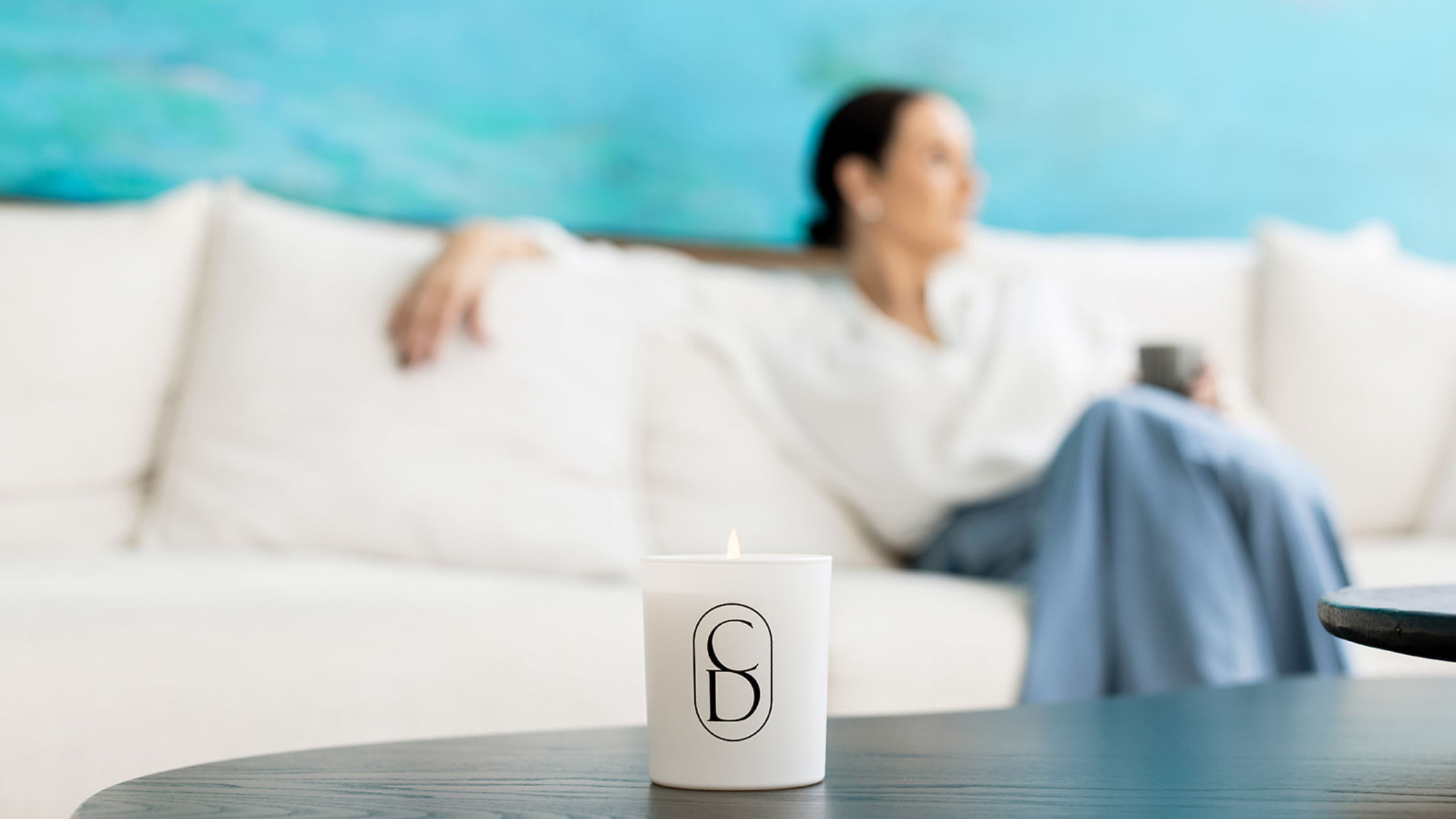 Person sitting on a couch with a blurred background, featuring a coffee mug on a table.