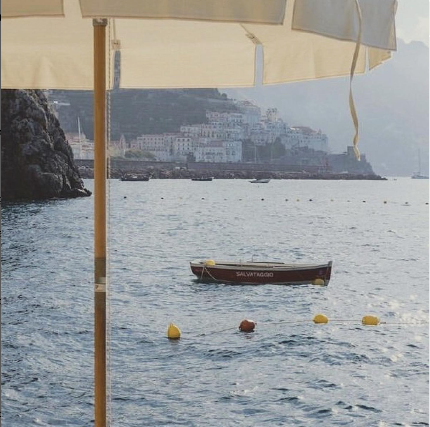 Boat in the water with a scenic background of buildings and mountains.
